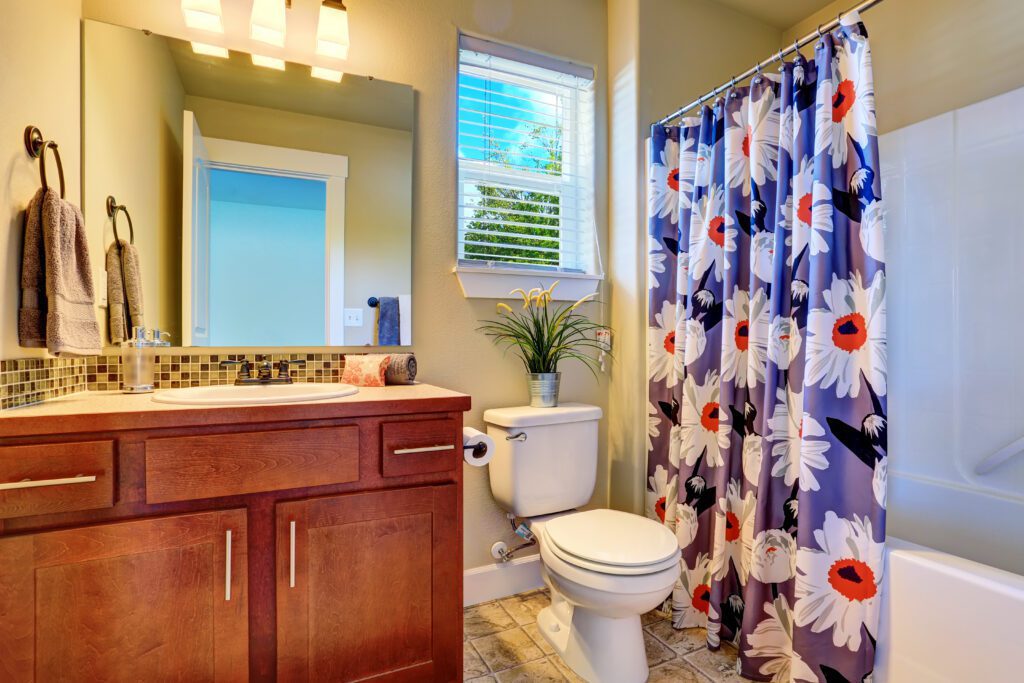 A bathroom with purple flowered shower curtains.