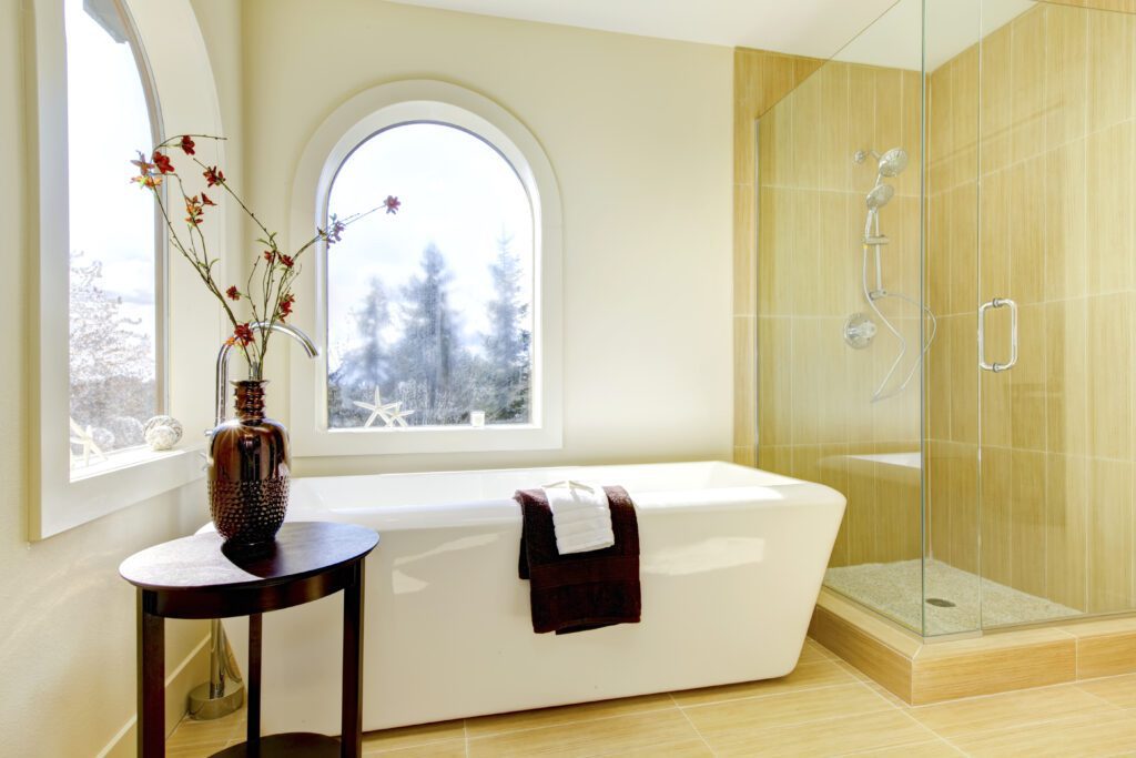 A bathtub and glass shower in a bright and airy space.